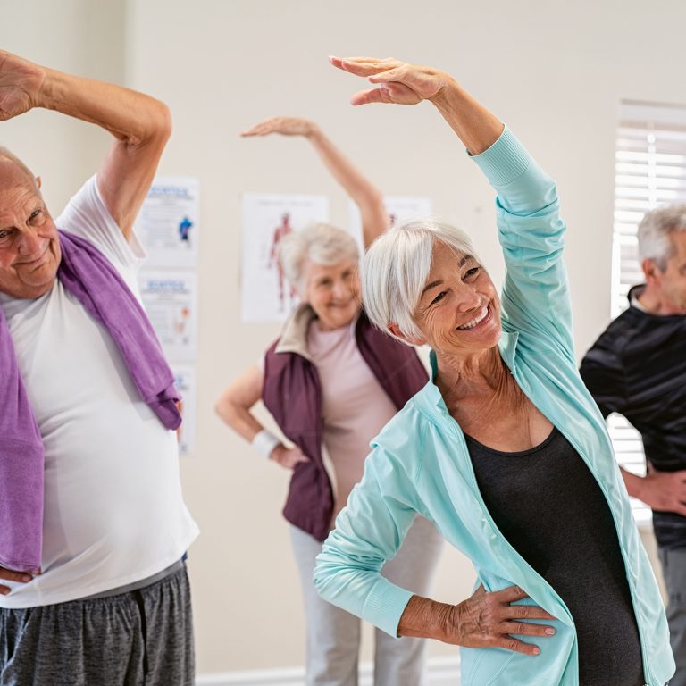 Group,Of,Seniors,Doing,Stretching,Exercise,Together,At,Retirement,Centre.